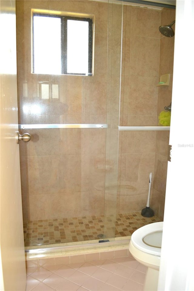 bathroom featuring walk in shower, tile patterned flooring, and toilet