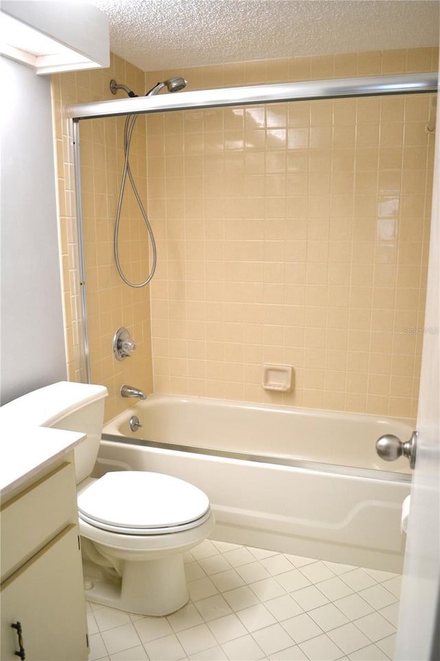 full bathroom featuring tiled shower / bath combo, tile patterned flooring, a textured ceiling, toilet, and vanity