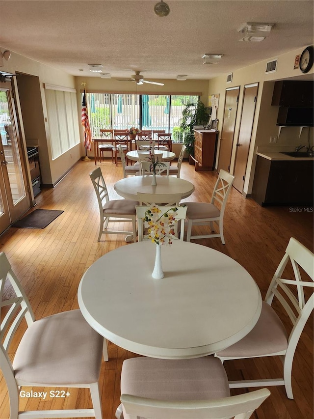 dining room with hardwood / wood-style floors, ceiling fan, and a textured ceiling