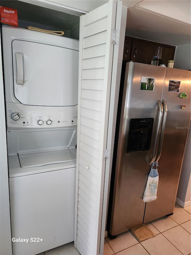 laundry area featuring light tile patterned floors and stacked washing maching and dryer