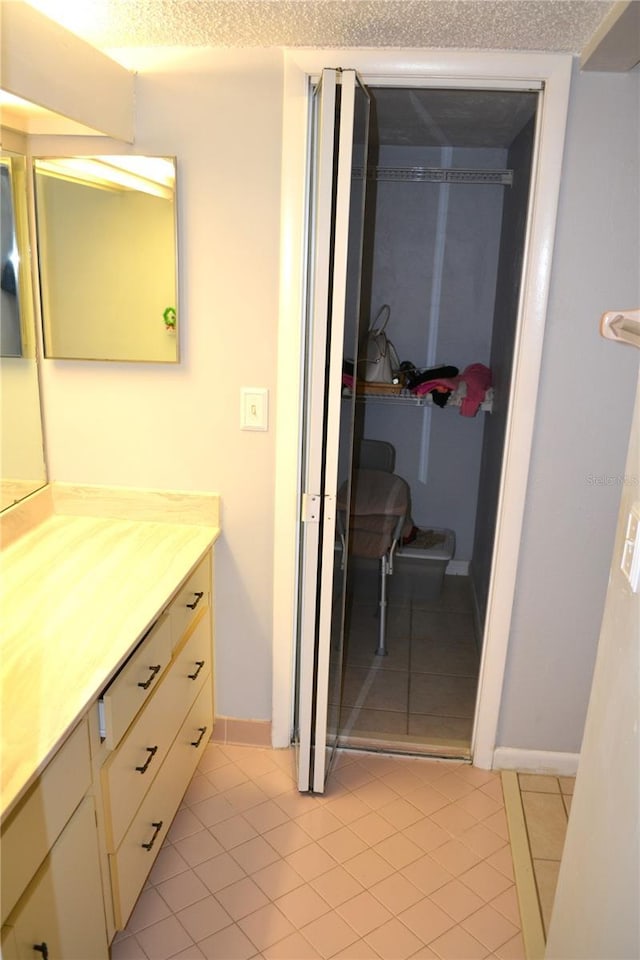 bathroom with tile patterned flooring, vanity, and a textured ceiling