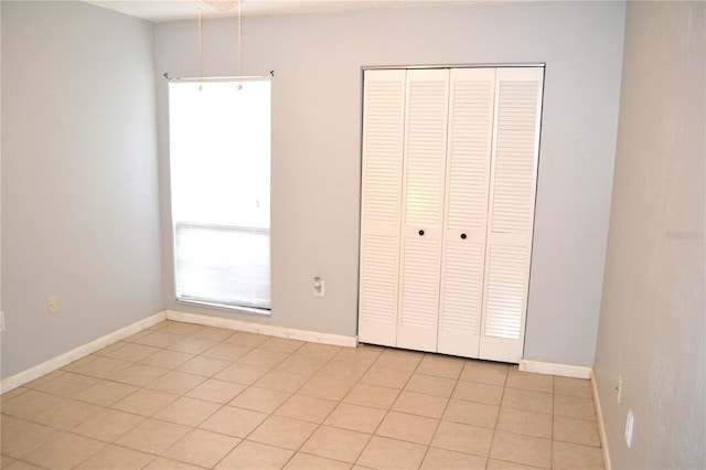 unfurnished bedroom featuring light tile patterned floors and a closet