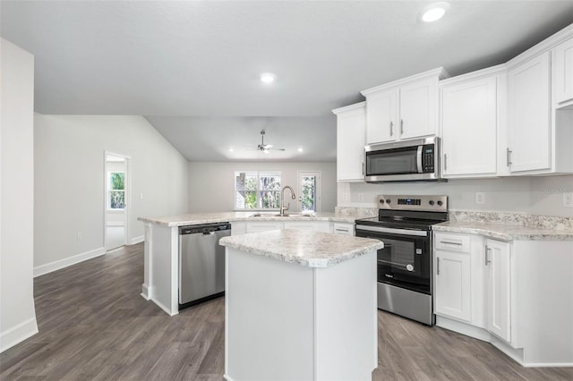 kitchen with appliances with stainless steel finishes, kitchen peninsula, sink, and white cabinets