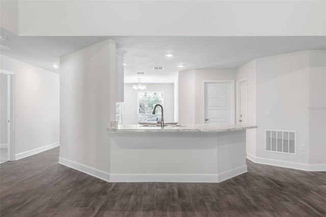 kitchen with sink, dark wood-type flooring, a notable chandelier, and kitchen peninsula