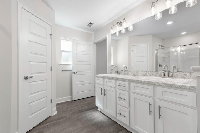 bathroom with hardwood / wood-style flooring, vanity, and a shower with shower door