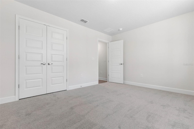 unfurnished bedroom with light colored carpet and a closet