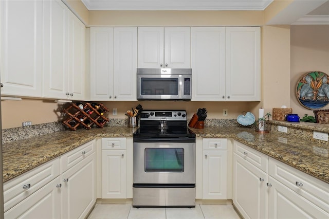 kitchen with white cabinets, light tile patterned flooring, stainless steel appliances, dark stone counters, and crown molding