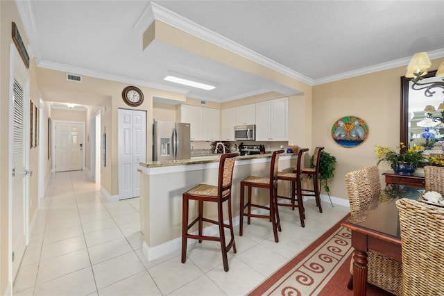 kitchen with ornamental molding, white cabinetry, kitchen peninsula, and appliances with stainless steel finishes