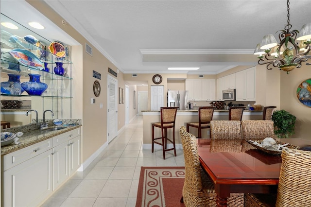 tiled dining area featuring ornamental molding, a chandelier, and sink