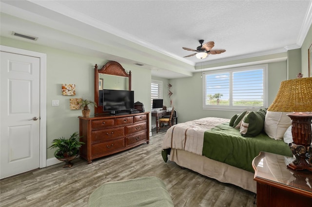 bedroom with a textured ceiling, crown molding, ceiling fan, and hardwood / wood-style flooring