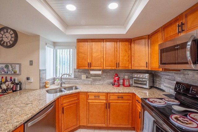 kitchen featuring sink, light stone countertops, stainless steel appliances, and a tray ceiling