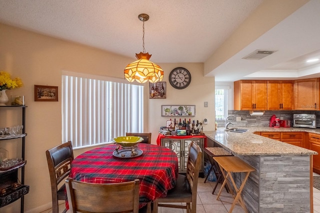 tiled dining room featuring a textured ceiling and sink