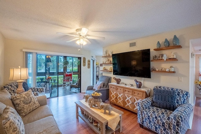 living room with ceiling fan, wood-type flooring, and a textured ceiling