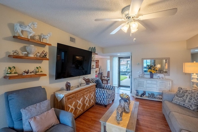 living room with hardwood / wood-style floors, a textured ceiling, and ceiling fan