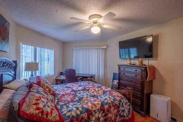 bedroom with light hardwood / wood-style flooring, a textured ceiling, and ceiling fan