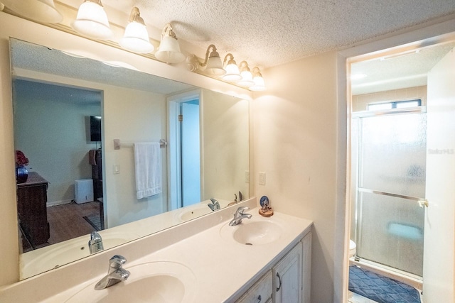 bathroom with vanity, an enclosed shower, a textured ceiling, and toilet