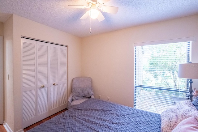 bedroom with a textured ceiling, wood-type flooring, a closet, and ceiling fan