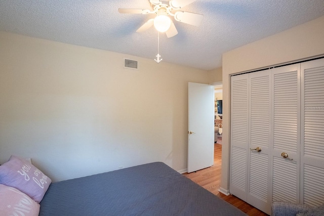 bedroom featuring a closet, a textured ceiling, light wood-type flooring, and ceiling fan