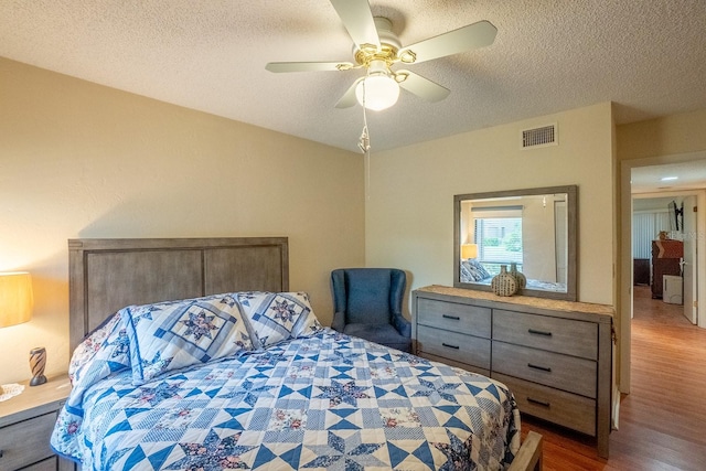 bedroom with a textured ceiling, hardwood / wood-style flooring, and ceiling fan