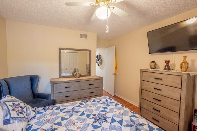 bedroom featuring light hardwood / wood-style flooring, a textured ceiling, and ceiling fan