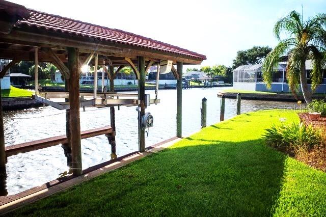 dock area with a water view, a lawn, and a lanai