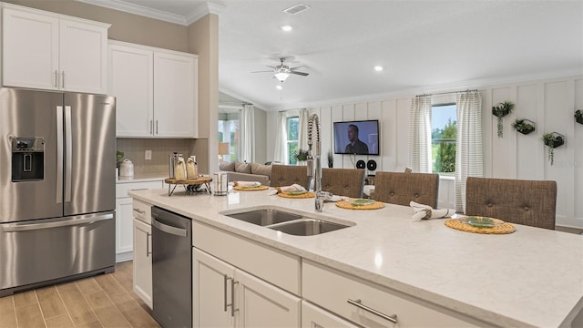 kitchen featuring ceiling fan, sink, ornamental molding, appliances with stainless steel finishes, and light stone countertops