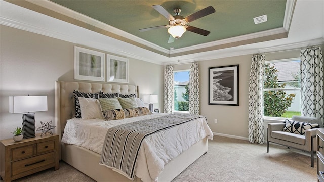 carpeted bedroom with ceiling fan, a raised ceiling, crown molding, and multiple windows