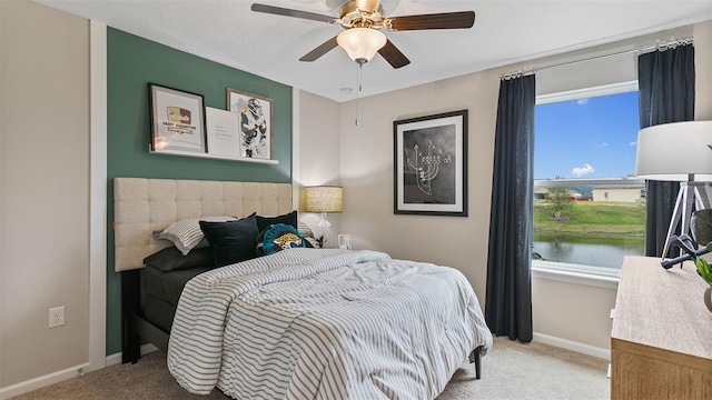 carpeted bedroom featuring a water view and ceiling fan