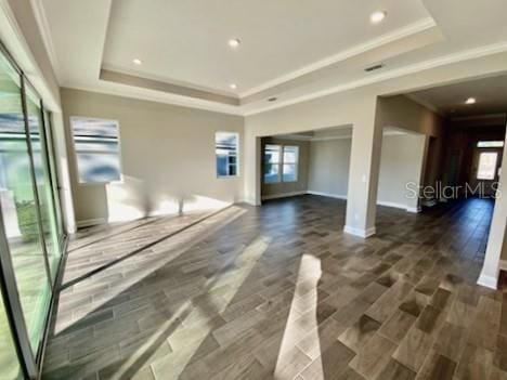 unfurnished living room featuring dark hardwood / wood-style flooring, a raised ceiling, and ornamental molding