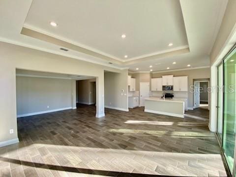 unfurnished living room with a raised ceiling and dark wood-type flooring