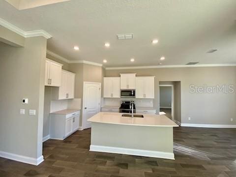 kitchen with dark wood-type flooring, white cabinets, sink, an island with sink, and stainless steel appliances