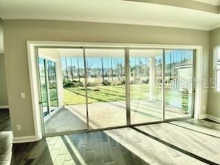 doorway with hardwood / wood-style floors, a wealth of natural light, and crown molding