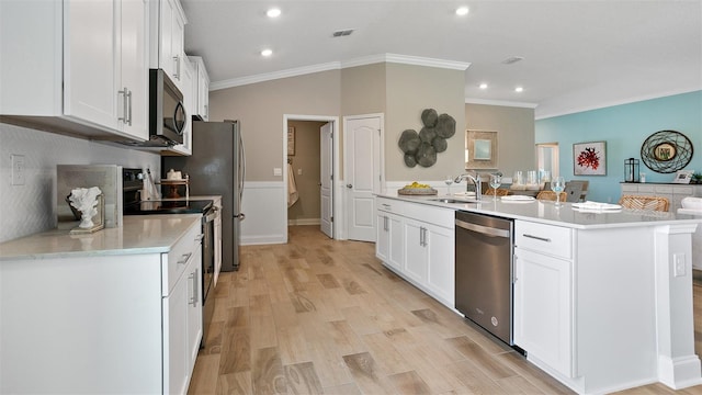 kitchen featuring crown molding, a center island with sink, white cabinetry, and stainless steel appliances