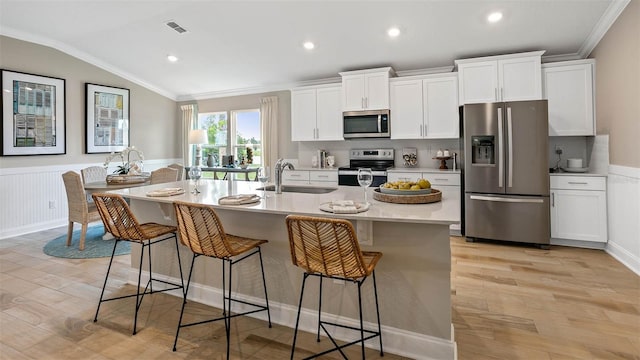 kitchen featuring a breakfast bar area, an island with sink, white cabinets, sink, and appliances with stainless steel finishes