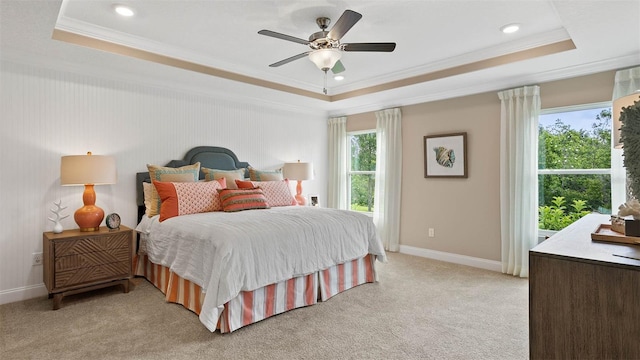 carpeted bedroom with ornamental molding, a tray ceiling, and ceiling fan