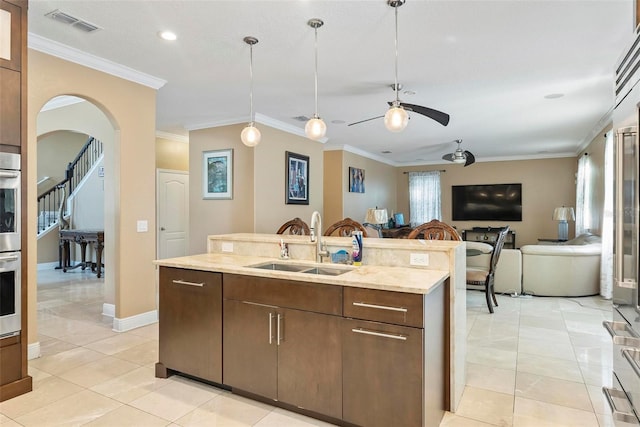 kitchen featuring ceiling fan, crown molding, and sink