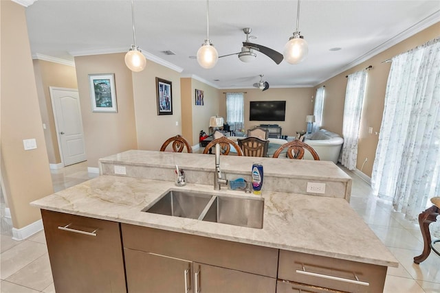 kitchen with light stone countertops, a center island with sink, hanging light fixtures, and sink