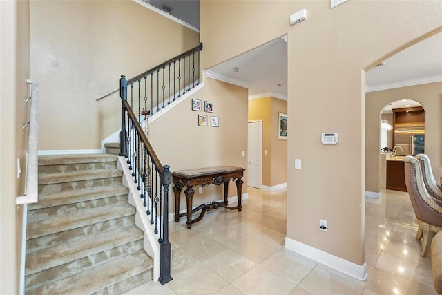 stairway with tile patterned flooring and crown molding