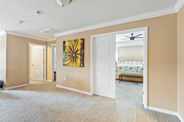 spare room with a textured ceiling, light colored carpet, ceiling fan, and ornamental molding