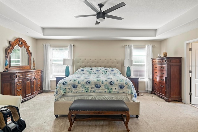 bedroom featuring a raised ceiling, ceiling fan, and light colored carpet