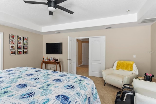 carpeted bedroom featuring ceiling fan and a raised ceiling