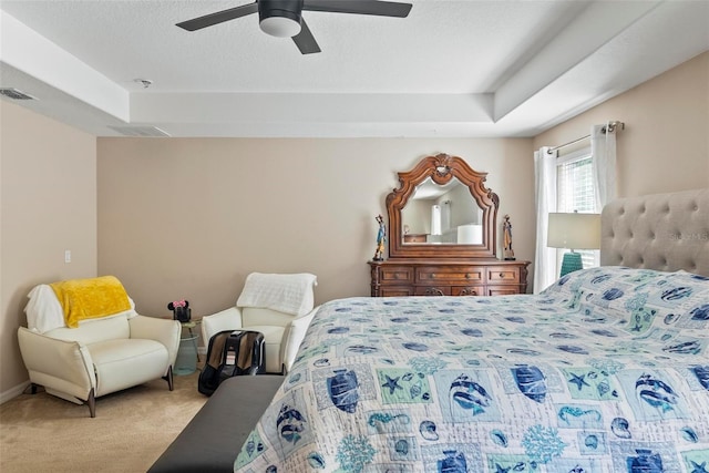 carpeted bedroom with a raised ceiling and ceiling fan