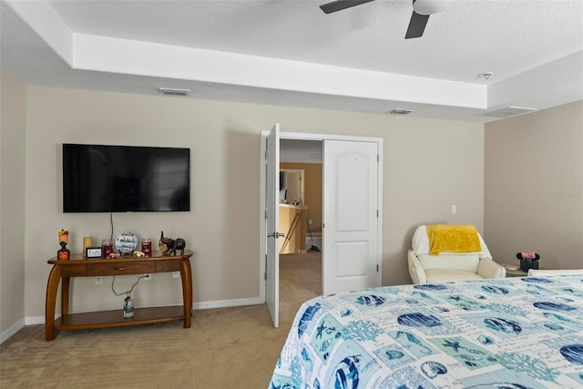 carpeted bedroom with a raised ceiling and ceiling fan