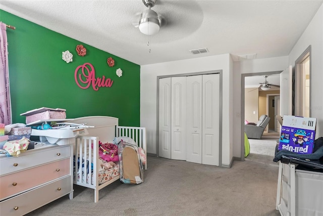 carpeted bedroom with a textured ceiling, a closet, and ceiling fan