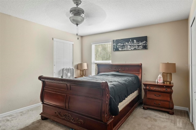 bedroom featuring ceiling fan, light colored carpet, and a textured ceiling