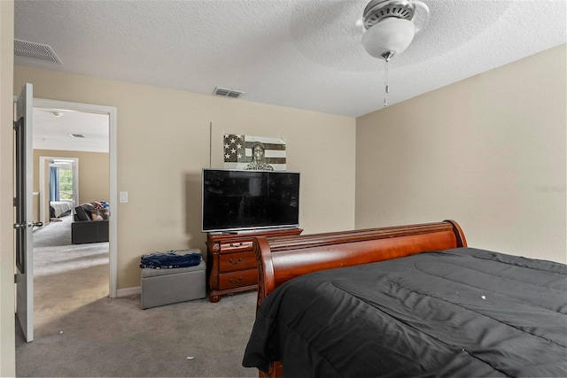 bedroom with ceiling fan, light carpet, and a textured ceiling