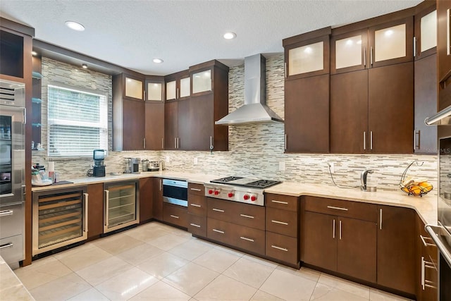 kitchen with wine cooler, wall chimney range hood, backsplash, and stainless steel gas cooktop