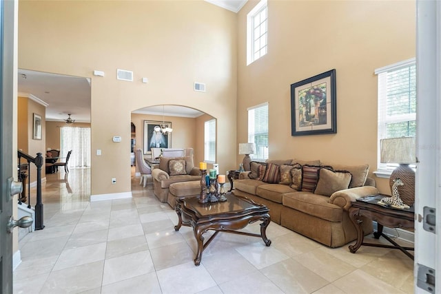 living room featuring light tile patterned floors, a healthy amount of sunlight, ceiling fan with notable chandelier, and ornamental molding