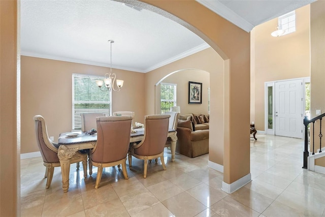 dining area featuring a textured ceiling, an inviting chandelier, ornamental molding, and light tile patterned flooring