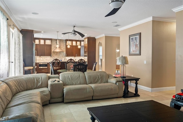 living room with ceiling fan, light tile patterned flooring, and ornamental molding